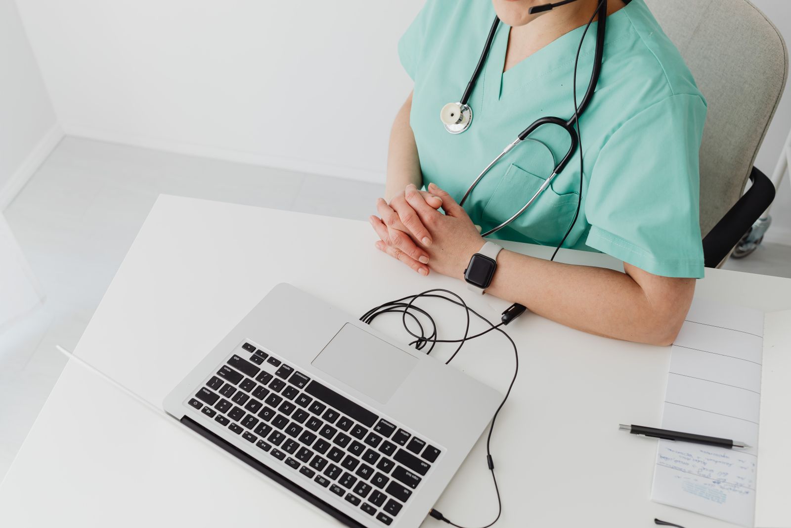 Soignante en tenue, mains posées devant son ordinateur portable